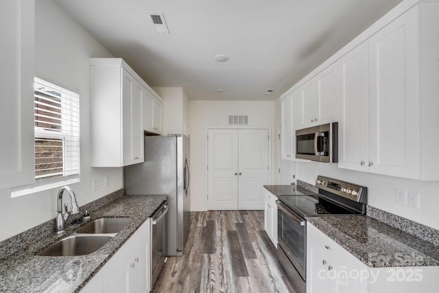 kitchen featuring appliances with stainless steel finishes, a sink, visible vents, and white cabinetry
