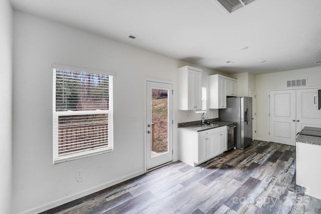 kitchen featuring visible vents, white cabinets, appliances with stainless steel finishes, dark wood-type flooring, and a sink