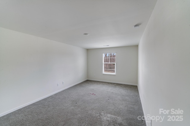 empty room featuring baseboards and carpet flooring