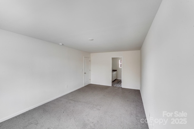 carpeted spare room featuring baseboards