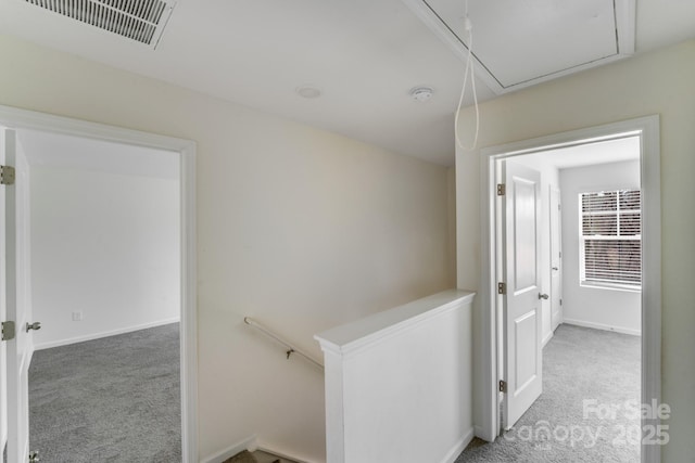 corridor featuring carpet flooring, an upstairs landing, baseboards, visible vents, and attic access