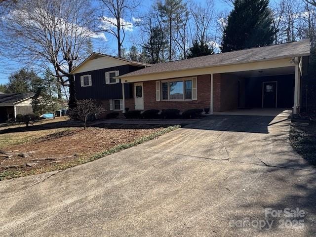 split level home with concrete driveway, an attached carport, and brick siding