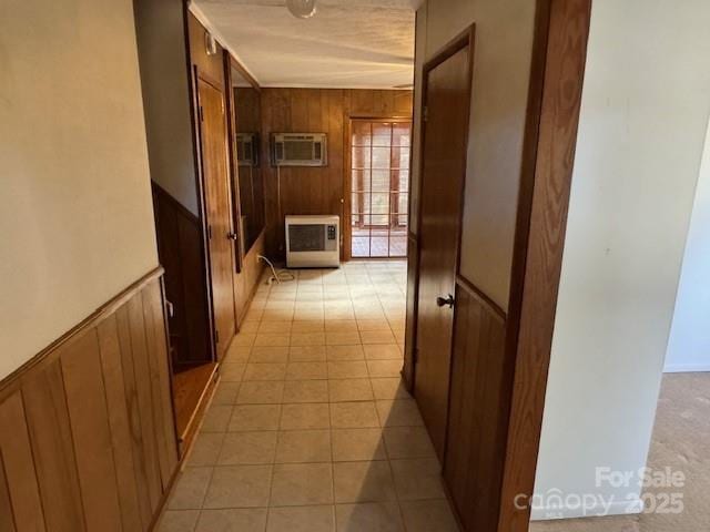 corridor featuring light tile patterned flooring, a wainscoted wall, wood walls, a wall mounted AC, and heating unit