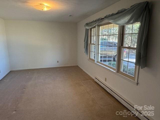 carpeted empty room with a baseboard radiator and baseboards