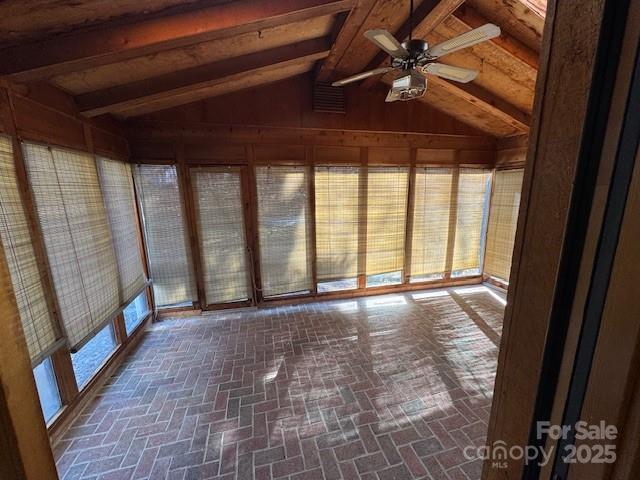 unfurnished sunroom featuring vaulted ceiling with beams and ceiling fan