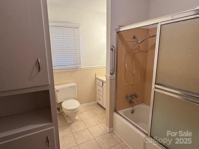 bathroom with toilet, combined bath / shower with glass door, vanity, baseboards, and tile patterned floors