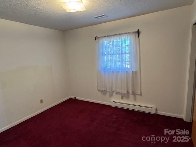 carpeted spare room featuring baseboards, a baseboard radiator, visible vents, and a textured ceiling