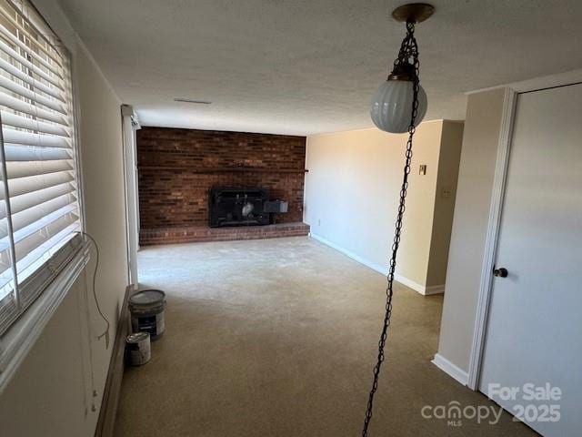 unfurnished living room featuring a textured ceiling, carpet floors, a brick fireplace, and baseboards