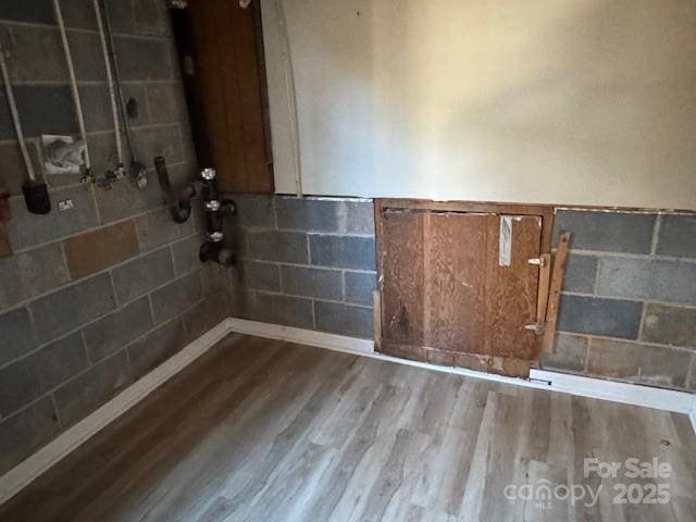 interior space with wainscoting, wood finished floors, and tile walls