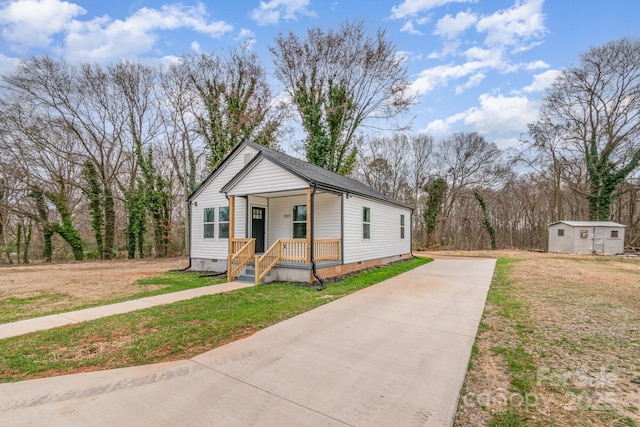 bungalow-style home with a front yard, crawl space, covered porch, and concrete driveway