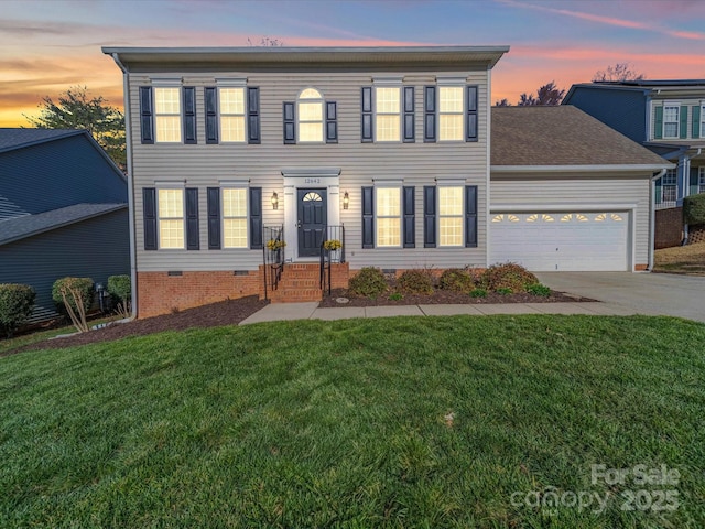 colonial-style house with crawl space, driveway, a garage, and a front yard