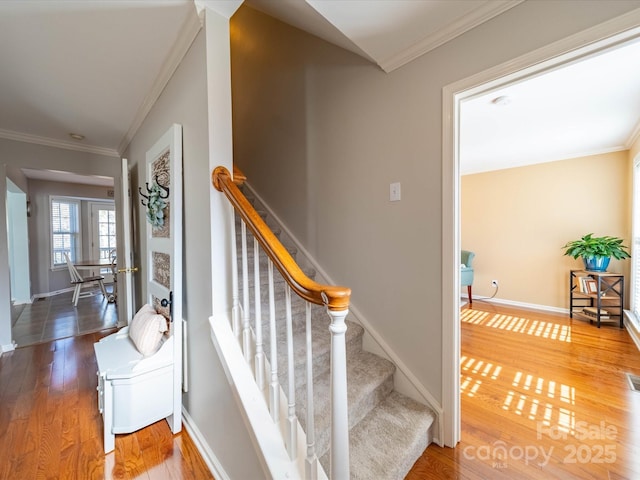 stairs with ornamental molding, wood finished floors, visible vents, and baseboards