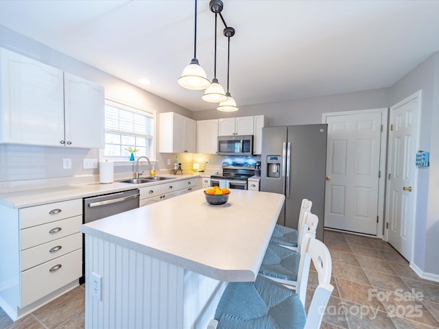 kitchen featuring a center island, light countertops, appliances with stainless steel finishes, white cabinets, and a sink