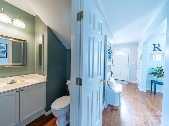 half bathroom featuring toilet, baseboards, ornamental molding, and wood finished floors