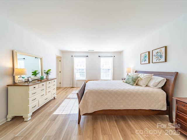 bedroom with visible vents, light wood-style flooring, and baseboards