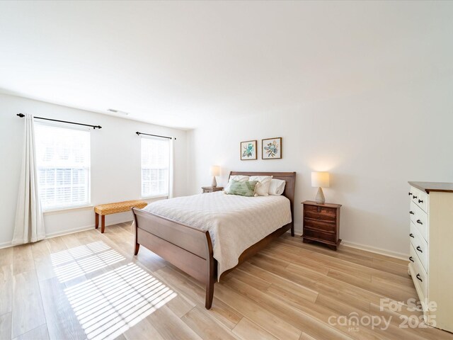 bedroom with baseboards, visible vents, and light wood-style floors