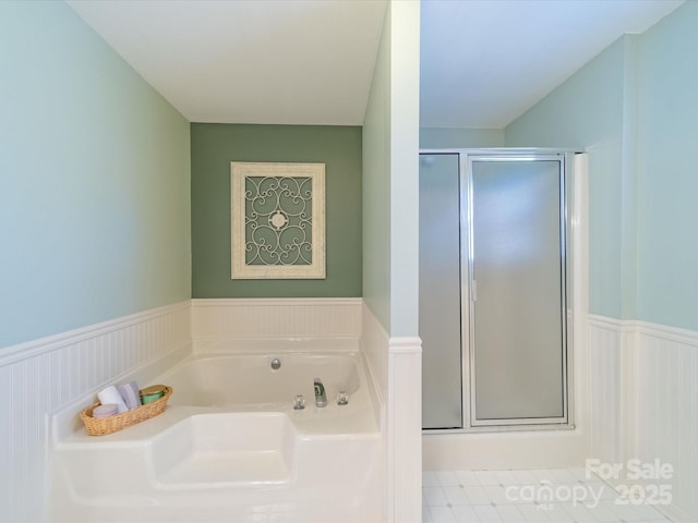 full bathroom with wainscoting, a garden tub, and a shower stall