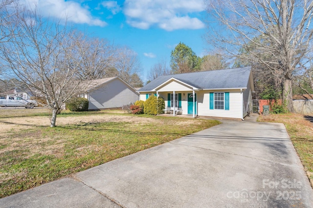 ranch-style home featuring a porch, a front yard, concrete driveway, and fence