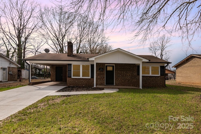 ranch-style home with an attached carport, brick siding, driveway, a front lawn, and a chimney