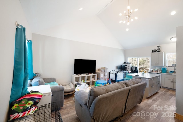 living room with high vaulted ceiling, light wood-type flooring, a notable chandelier, and recessed lighting