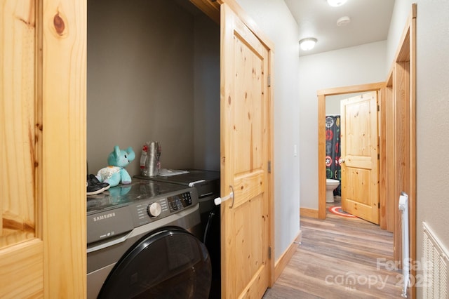 washroom featuring radiator, laundry area, baseboards, and wood finished floors