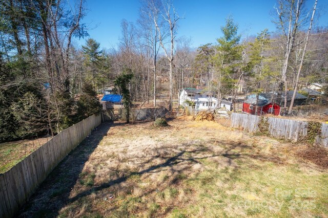 view of yard featuring fence and a wooded view