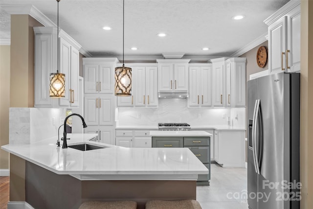 kitchen with a breakfast bar area, appliances with stainless steel finishes, a peninsula, crown molding, and a sink