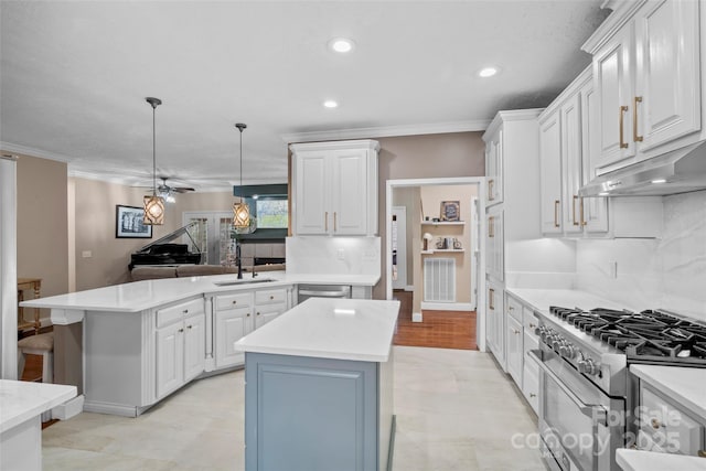 kitchen featuring a peninsula, appliances with stainless steel finishes, a sink, and light countertops