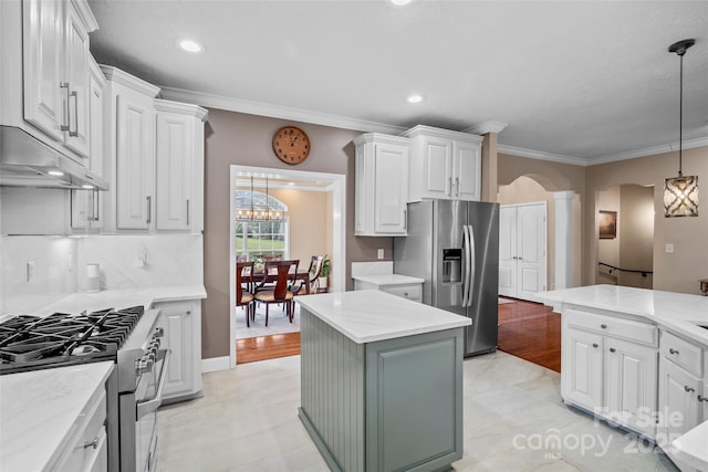 kitchen featuring arched walkways, white cabinetry, light countertops, appliances with stainless steel finishes, and crown molding