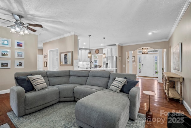 living area with arched walkways, dark wood-style flooring, a textured ceiling, and ornate columns