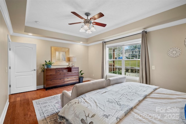 bedroom with ceiling fan, crown molding, baseboards, and wood finished floors