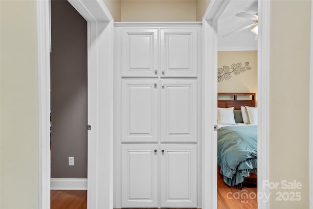 corridor with baseboards and wood finished floors