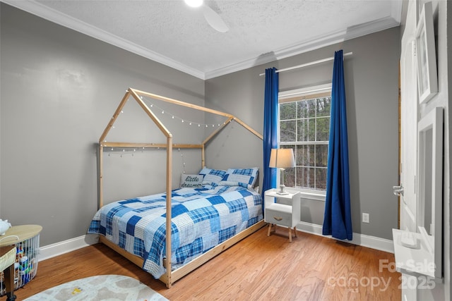 bedroom featuring crown molding, a textured ceiling, baseboards, and wood finished floors