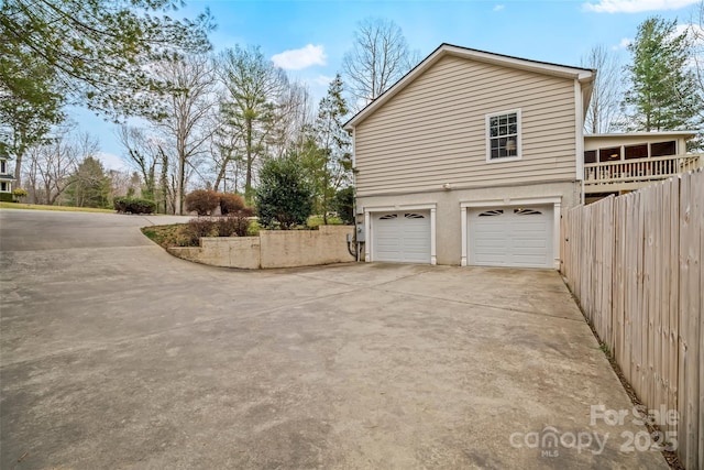 view of side of home featuring driveway, an attached garage, and stucco siding