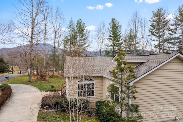 view of side of home with roof with shingles