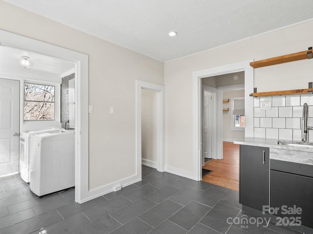 interior space with a sink, baseboards, washing machine and dryer, light countertops, and open shelves