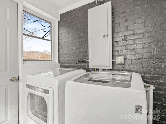 laundry area featuring electric panel, separate washer and dryer, brick wall, crown molding, and laundry area