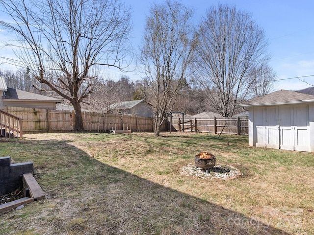 view of yard featuring an outbuilding, a fire pit, and a fenced backyard