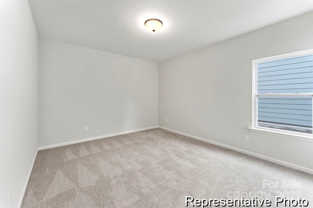 unfurnished room with light carpet and baseboards