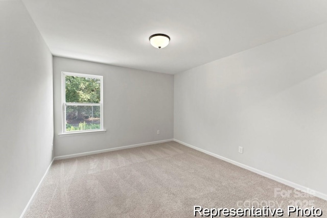 spare room with light carpet and baseboards