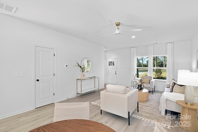 living area with light wood finished floors, ceiling fan, visible vents, and baseboards