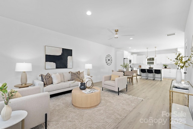 living area with light wood-style floors, recessed lighting, visible vents, and ceiling fan