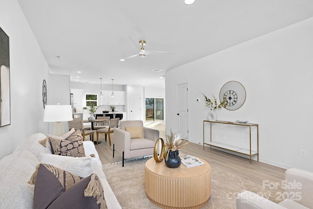 living room with recessed lighting, plenty of natural light, a ceiling fan, and light wood-style floors