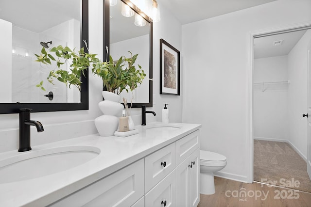 full bathroom with a sink, a spacious closet, toilet, and double vanity