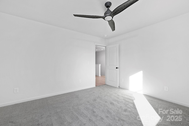 carpeted spare room featuring ceiling fan and baseboards