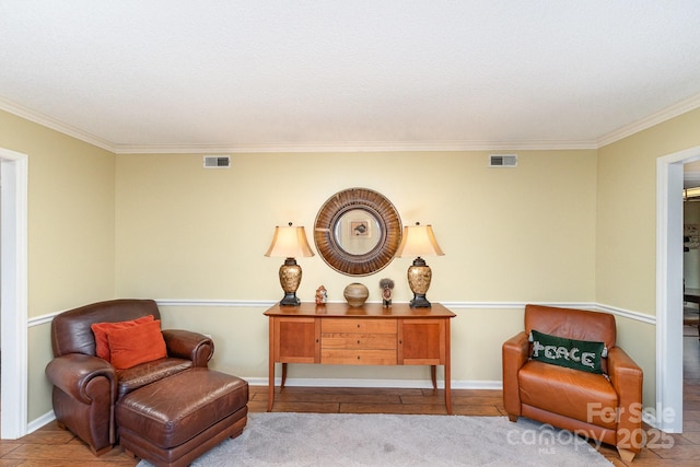 living area with visible vents, crown molding, and baseboards