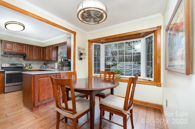 dining space with crown molding, baseboards, and light wood-type flooring