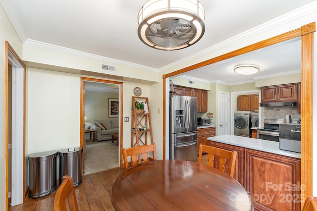 dining room with washing machine and clothes dryer, visible vents, crown molding, hardwood / wood-style floors, and a ceiling fan