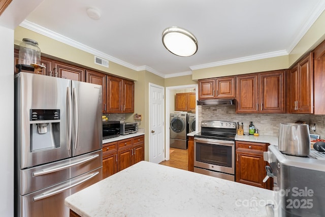 kitchen with visible vents, under cabinet range hood, appliances with stainless steel finishes, independent washer and dryer, and backsplash