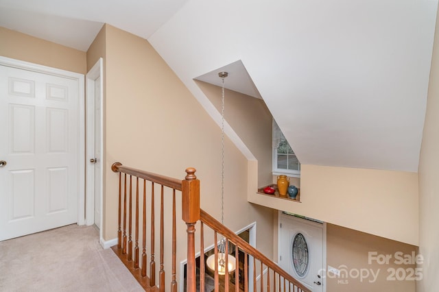 hall with an upstairs landing, carpet, and lofted ceiling